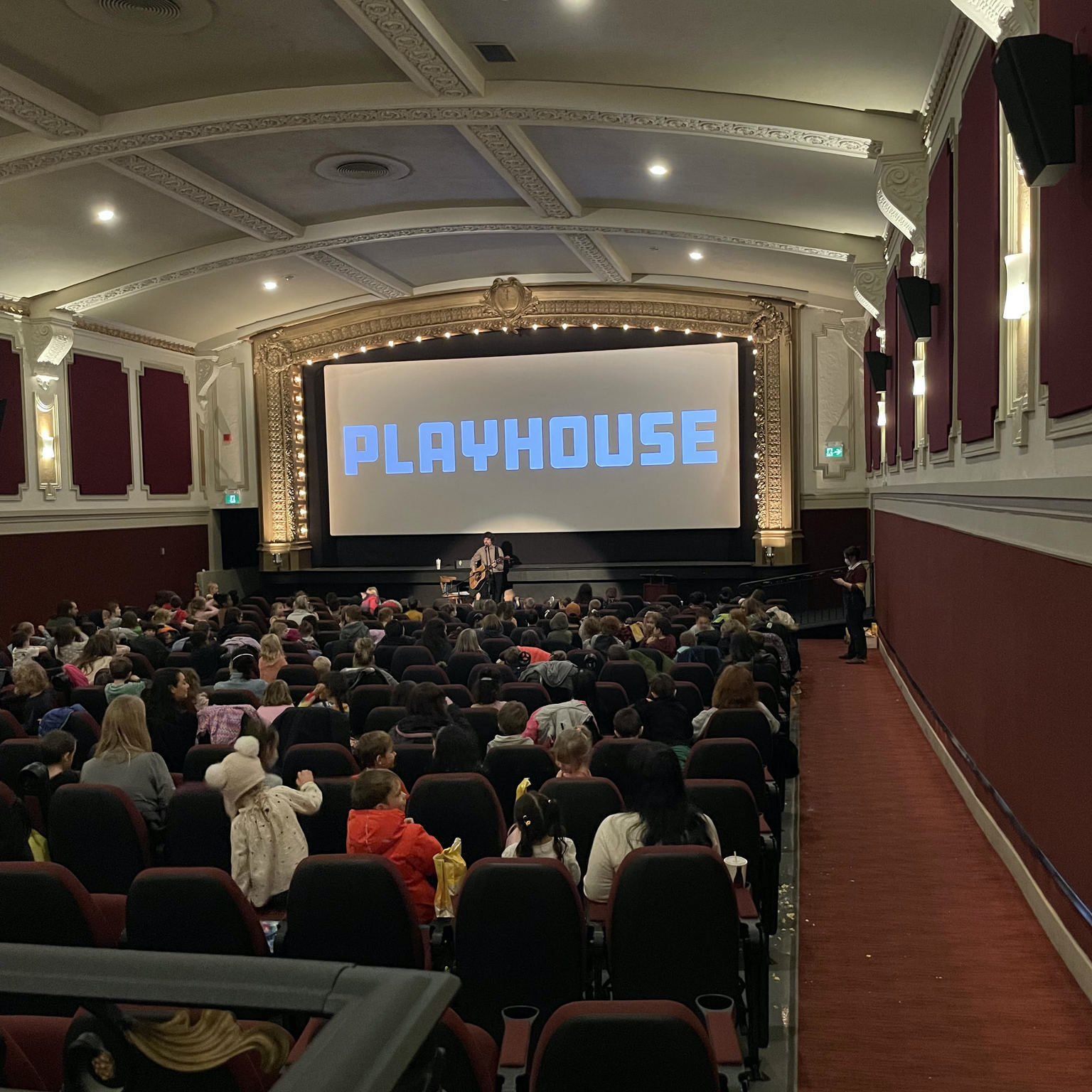 matt ellis performing and teaching for a large group of families at the playhouse theatre